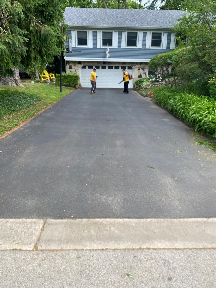 Asphalt driveway leading to a two-story home with dark shutters