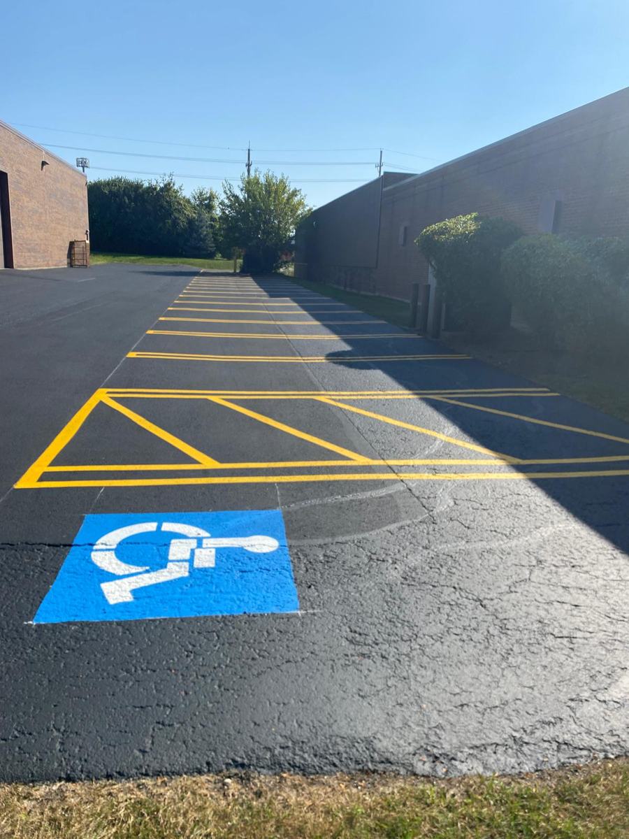 Accessible parking space and yellow access aisle markings beside a commercial building